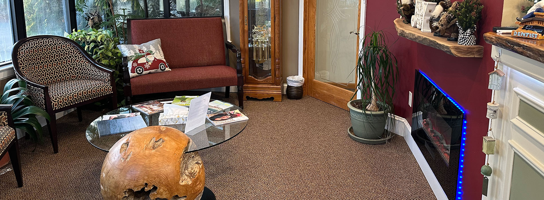 The image shows an interior space with a waiting area featuring a couch, coffee table, plants, and a reception desk with a sign.