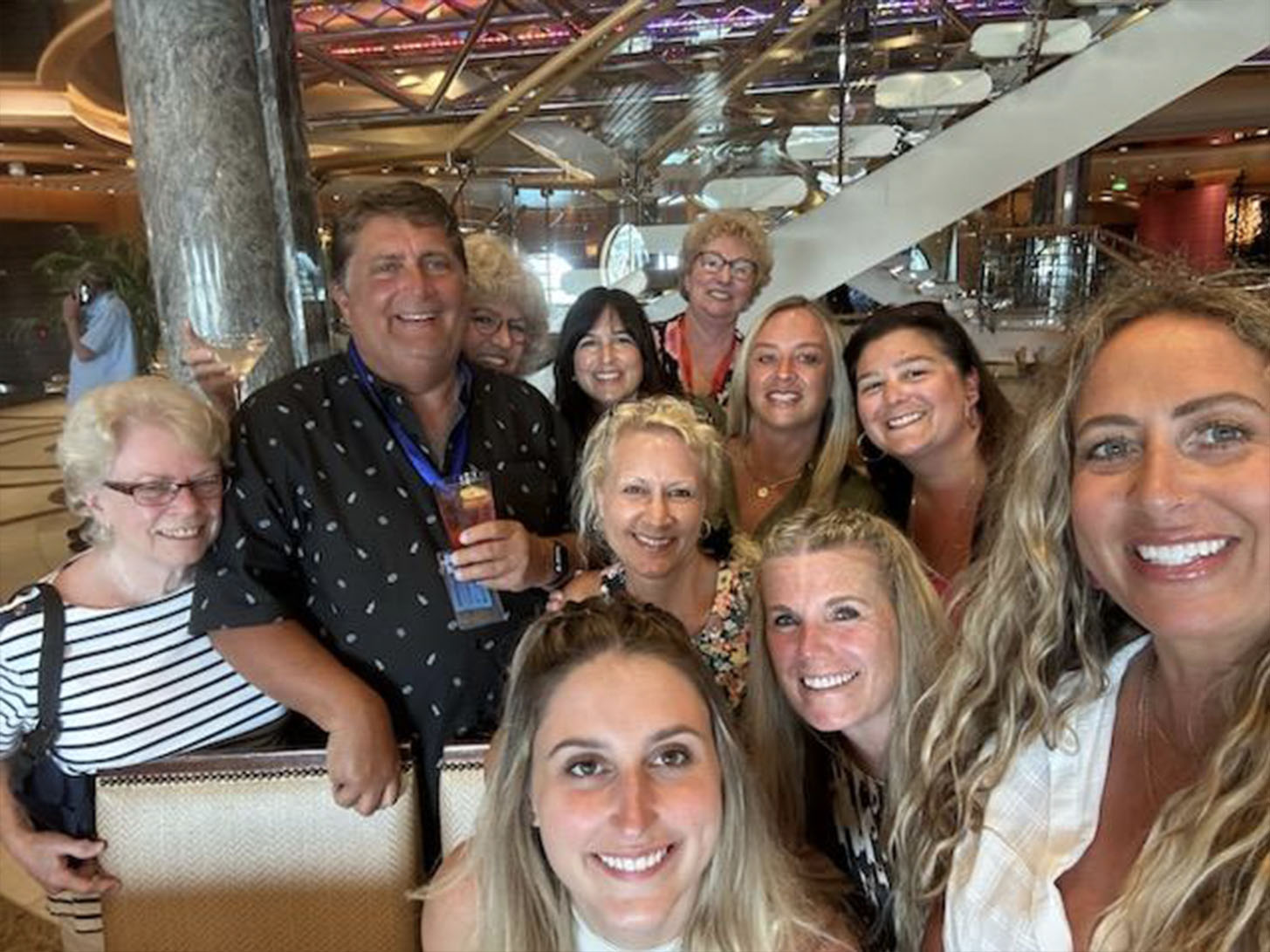 A group of people posing together for a photo at an event, with a man standing behind them holding a microphone.