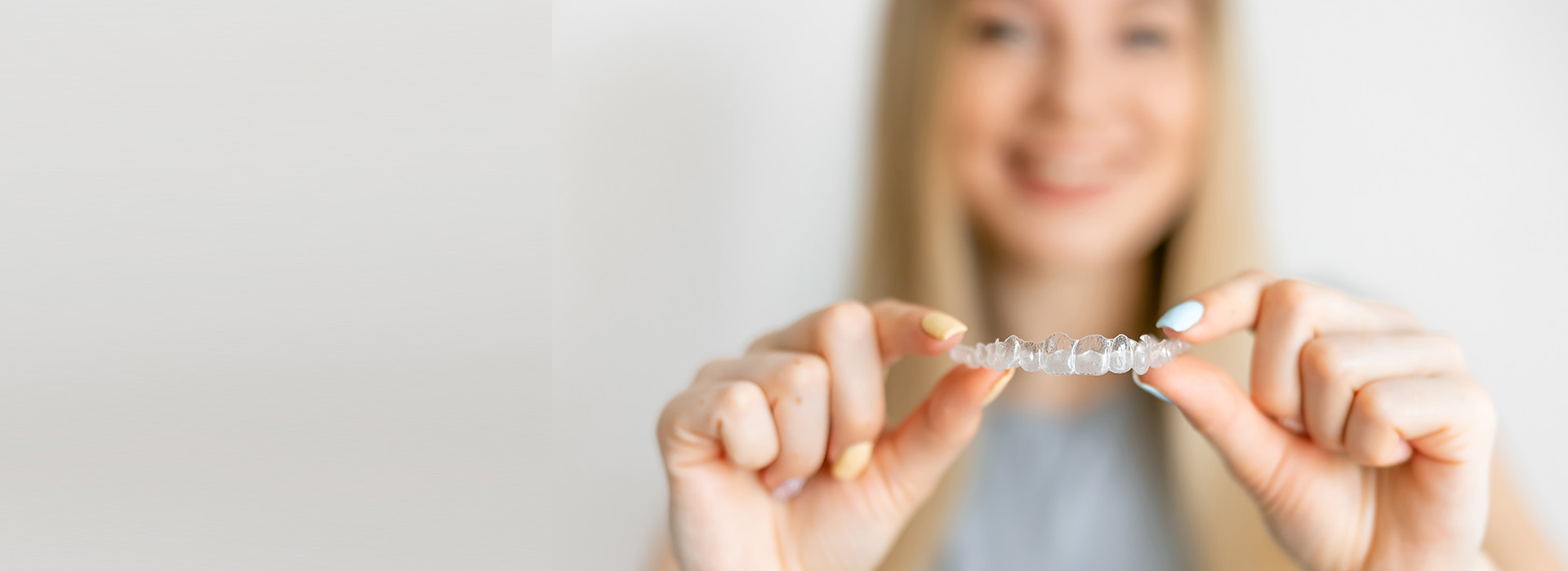 A woman holding a small object with her fingers, set against a blurred background.