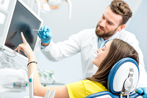 A man and woman in a medical setting with electronic devices, where the man is pointing at something on a computer screen while the woman looks on attentively.